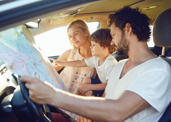 Urlaubsziel mit Kindern aussuchen - Familie sitzt im Auto