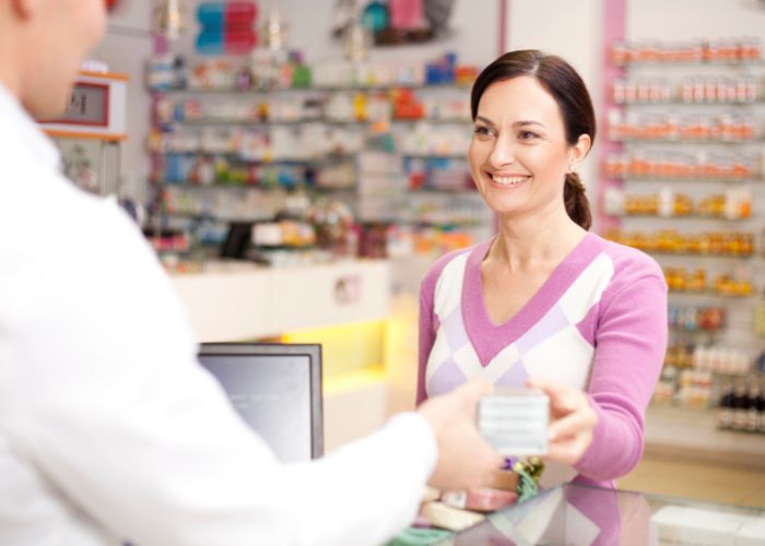 Una mujer comprando Omni Biotic 6 en la farmacia